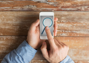 close up of hands with magnifier on smartphone