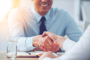 Good deal. Close-up of two business people shaking hands while sitting at the working place